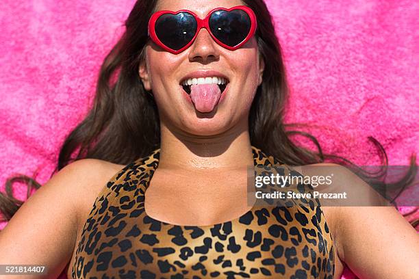 portrait of young woman sunbathing pulling a face - bronzage humour photos et images de collection