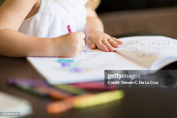 cropped shot of girl coloring in book with crayons - coloring book stock pictures, royalty-free photos & images