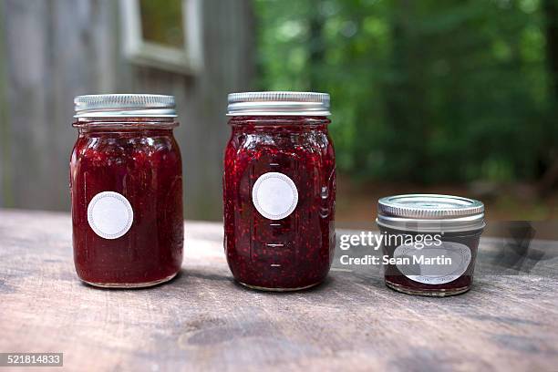 three jars of jam on garden table - strawberry jam stock pictures, royalty-free photos & images