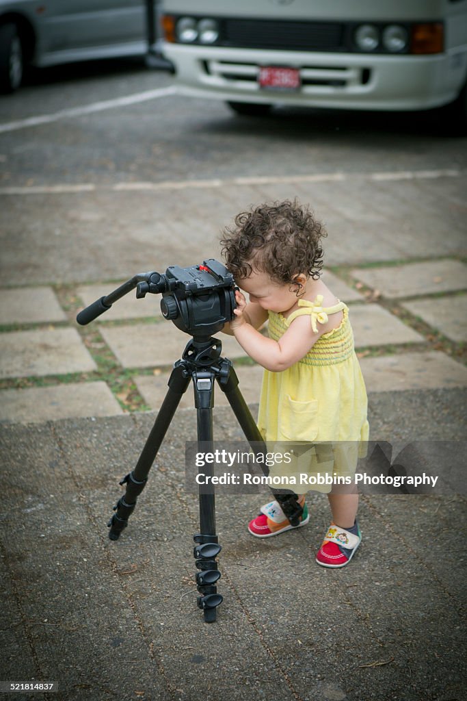 Cute baby girl playing with a tripod