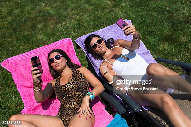 two sisters taking selfies whilst sunbathing on loungers in garden - pink vanity stock pictures, royalty-free photos & images