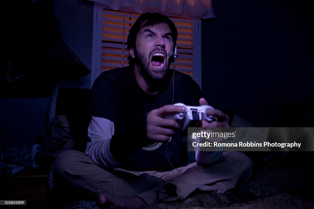 Mid adult man shouting whilst playing video game at night
