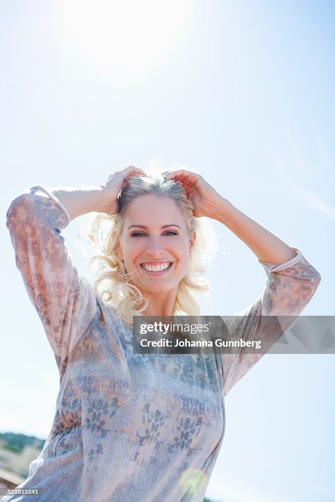 Woman posing against sunny sky