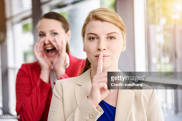 businesswomen hiding and letting out secret - shhhh stockfoto's en -beelden