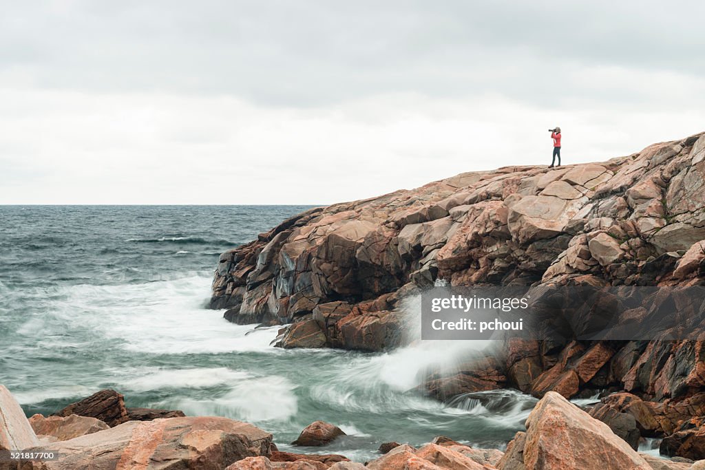 Nature photographer on coastline, woman photographing