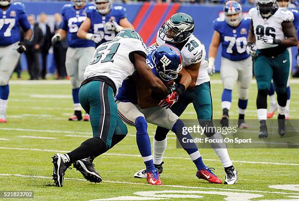 Rueben Randle of the New York Giants gets tackled by Emmanuel Acho and Cary Williams of the Philadelphia Eagles during an NFL football game at...