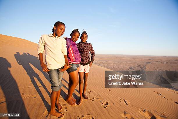 girls posing, sand dune, walvis bay, namibia - jake warga stock pictures, royalty-free photos & images