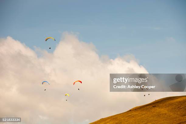 paraponters flying from the side of pendle hill, above clitheroe in lancashire, uk. - hang parachute stock-fotos und bilder