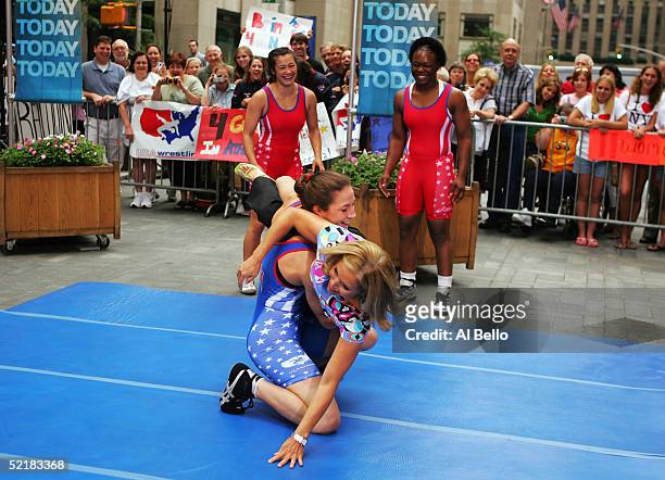 Sara McMann of the U.S. Olympic women's wrestling team flips Katie Couric of the Today Show as Tela O'Donnell and Toccara Montgomery look on during...