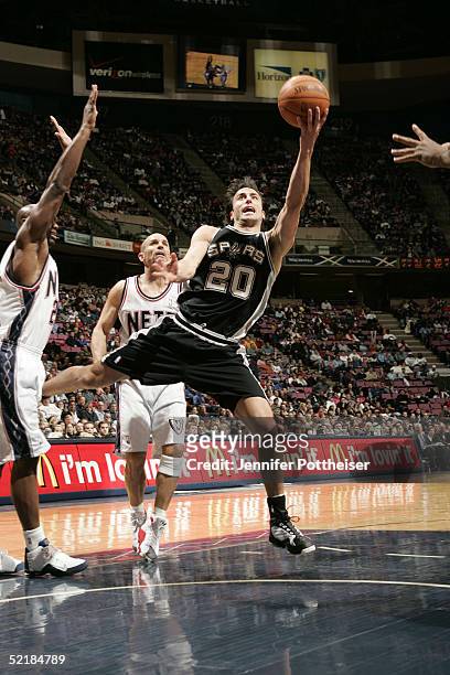 Manu Ginobili of the San Antonio Spurs drives as Billy Thomas and Jason Kidd of the New Jersey Nets defend on February 11, 2005 at the Continental...