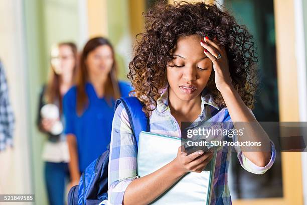 african american college student looking upset while reading text - cell phone confused stockfoto's en -beelden