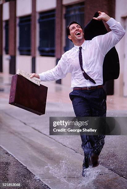 carefree businessman in the rain - kicking bag stock pictures, royalty-free photos & images