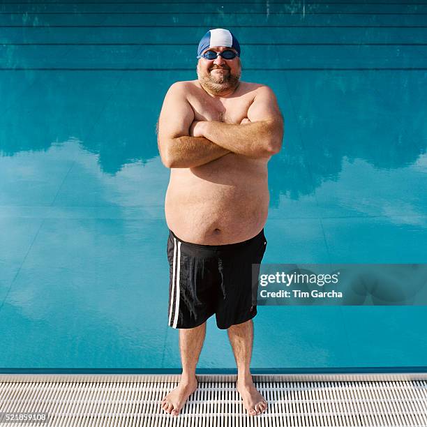 man standing with crossed arms in front of pool - zwembroek stockfoto's en -beelden