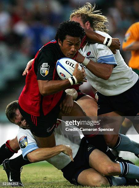 Casey Laulala of the Crusaders is tackled during the Super 12 trial match between the NSW Waratahs and the Crusaders at Aussie Stadium February 12,...