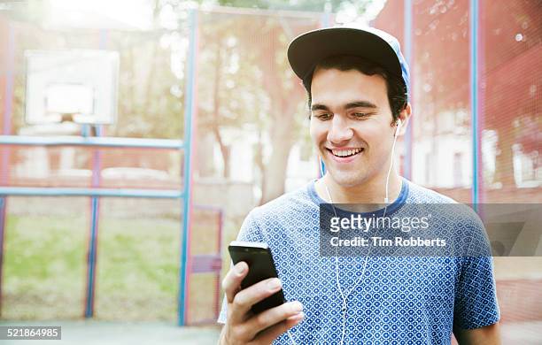 young man with smart phone and headphones - young man holding basketball stockfoto's en -beelden