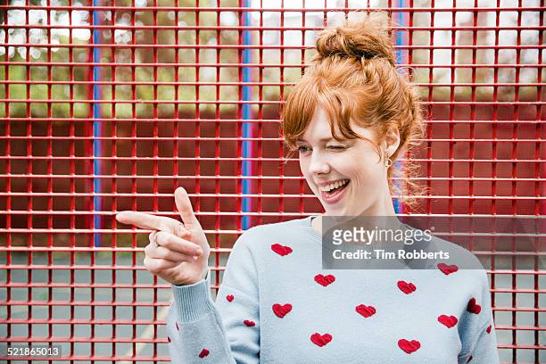 young woman winking and pointing. - gesturing foto e immagini stock