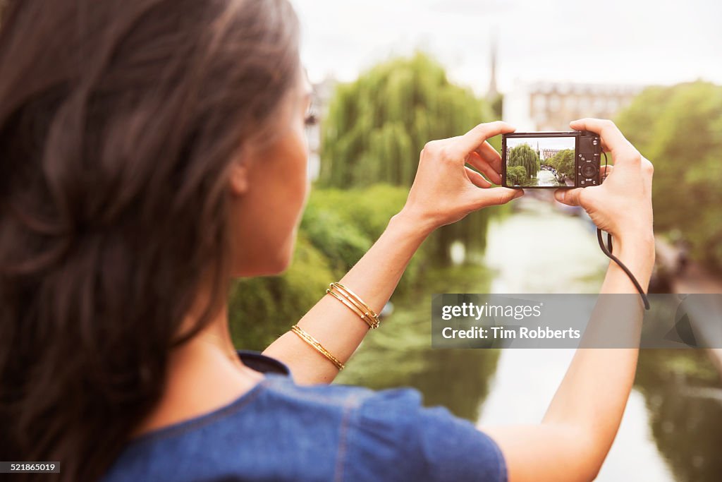 Young woman taking photo of canal.