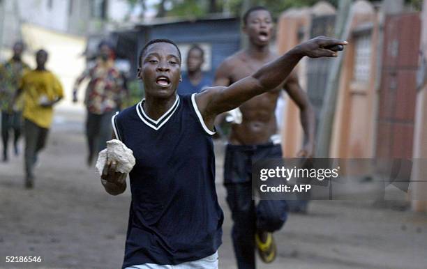 Rioter carry stones to throw to anti riots policemen shooting tear gases at them in Lome 12 February, 2005. Two people were killed and two policemen...