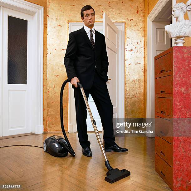 young man wearing suit vacuuming - huisman stockfoto's en -beelden