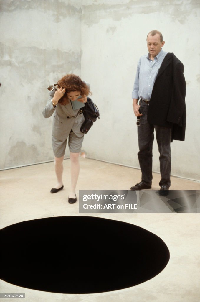 Two Visitors Inside the Art Installation Descent into Limbo by Anish Kapoor