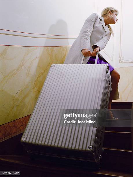 young woman pulling suitcase up stairs - dragging fotografías e imágenes de stock