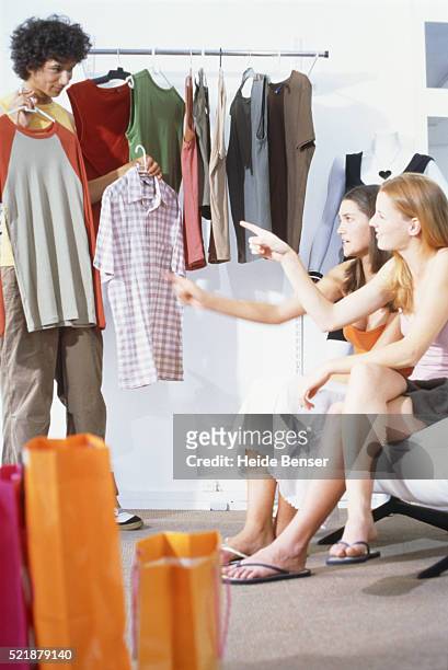 teenage boy showing teenage girls clothing in shop - teenager boy shopping stock-fotos und bilder