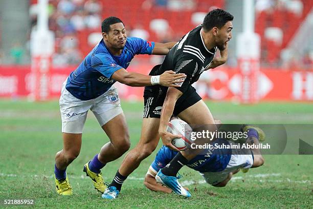 Ted Stanaway of New Zealand is tackled Ed Fidow of Samoa during the 2016 Singapore Sevens Plate Final between New Zealand and Samoa at National...