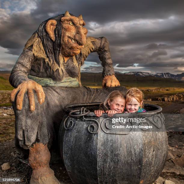 little girls playing in a large caldron with statue of gryla. iceland - cauldron stock pictures, royalty-free photos & images