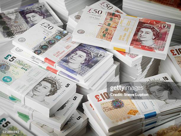 bundles and piles of uk banknotes - british currency stockfoto's en -beelden