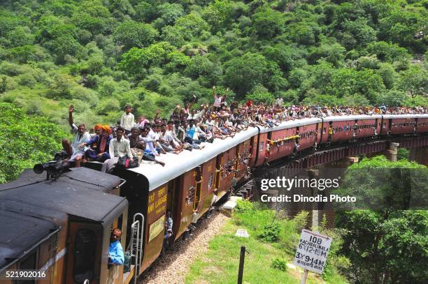 people taking risk while travelling on roof of train going on bridge, rajasthan, india - india train stock-fotos und bilder