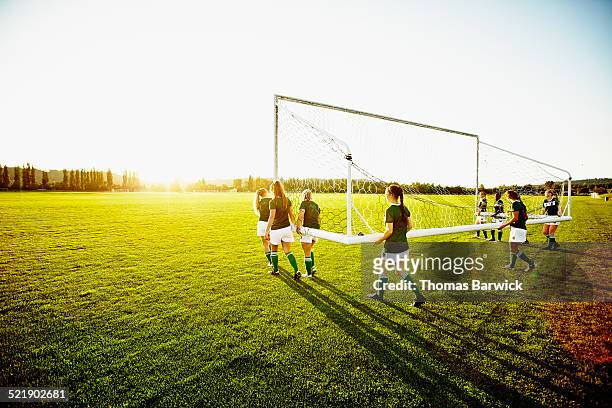 soccer teammates carrying goal out onto field - local soccer field stock pictures, royalty-free photos & images