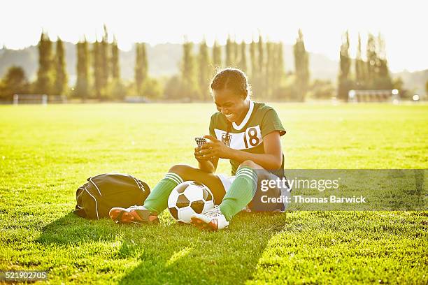 soccer player checking messages on smartphone - jamaican girl stock pictures, royalty-free photos & images