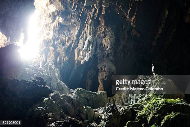 man inside underground cave standing on a rock - vang vieng imagens e fotografias de stock