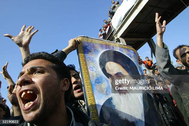 File picture taken 19 January 2004 showing Iraqi Shiite Muslims hold up a poster of leading Shiite cleric Grand Ayatollah Ali al-Sistani in the...