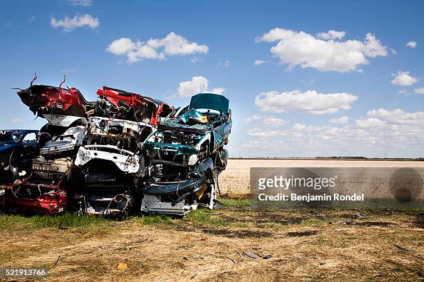 stack of junked cars beside a field - junkyard stock pictures, royalty-free photos & images