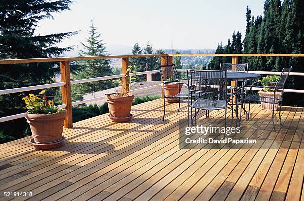 metal table and chairs on deck - holzterrasse stock-fotos und bilder