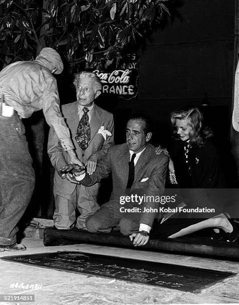 Actor Humphrey Bogart leaving his hand print in concrete on the Hollywood Walk of Fame, with his wife Lauren Bacall and Sid Grauman , for Warner Bros...