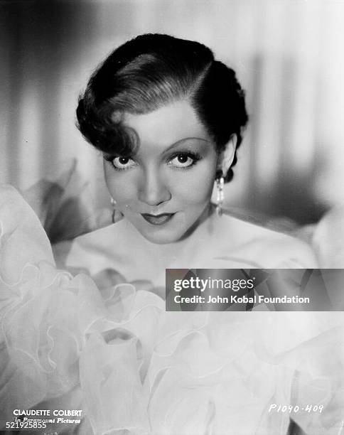 Portrait of actress Claudette Colbert surrounded by ruffles material, for Paramount Pictures, 1929.