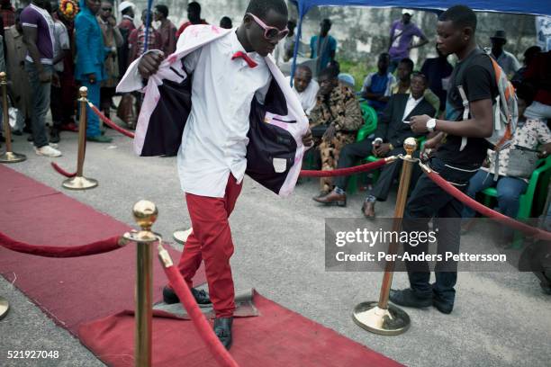 Young Sapeur parades and shows his designer label clothes, including Versace, while paying their respect to Stervos Nyarcos, the founder of the...