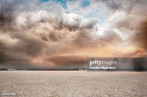 salt flat landscape with stormy sky and mountains - intimidation stock pictures, royalty-free photos & images