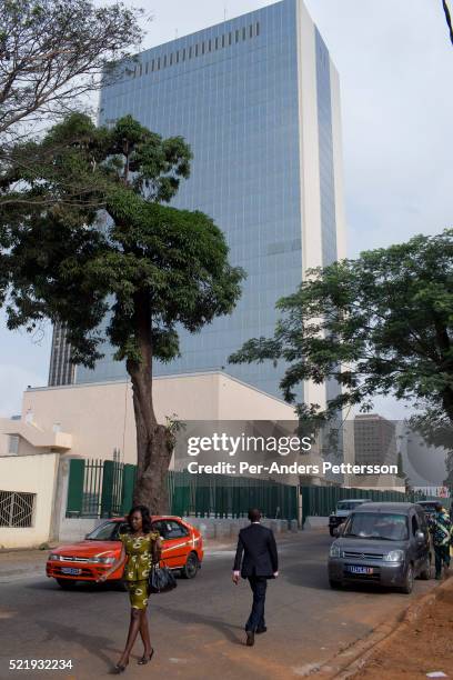 People walk past the provisional headquarters of the African Development Bank in Abidjan, Ivory Coast. The Bank moved to Tunisia over 10 years ago...