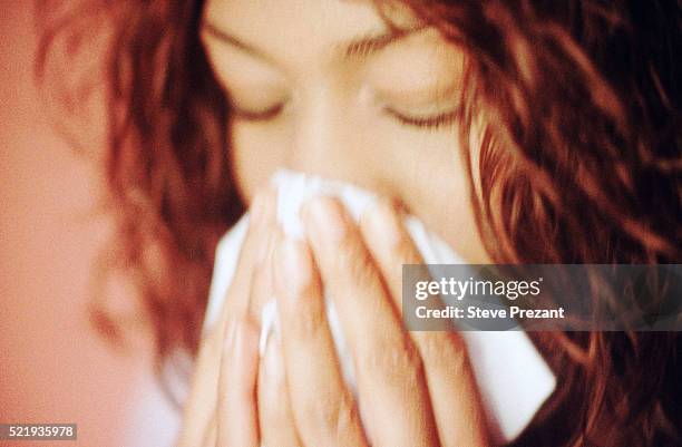 young woman blowing her nose - closeup of a hispanic woman sneezing foto e immagini stock