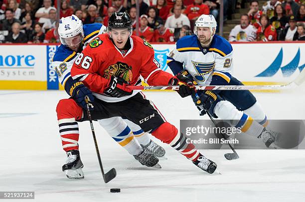 Teuvo Teravainen of the Chicago Blackhawks and David Backes of the St. Louis Blues chase the puck in front of Patrik Berglund in the first period of...