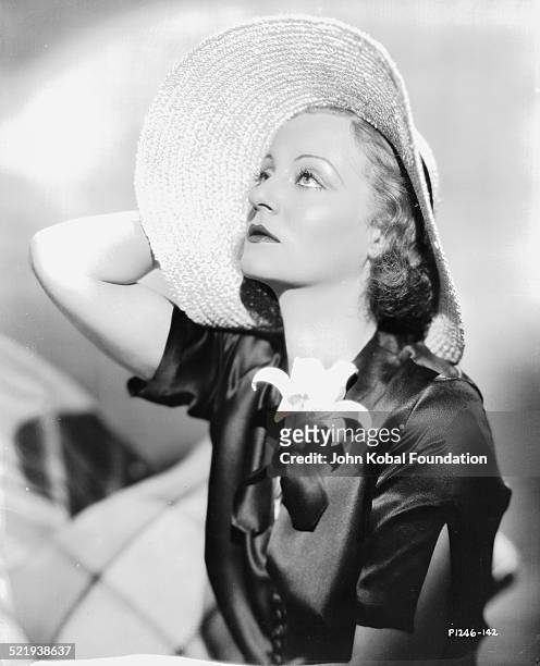 Actress Tallulah Bankhead , in a promotional shot for Paramount Pictures, wearing a black satin dress and a wide brimmed hat, 1932.