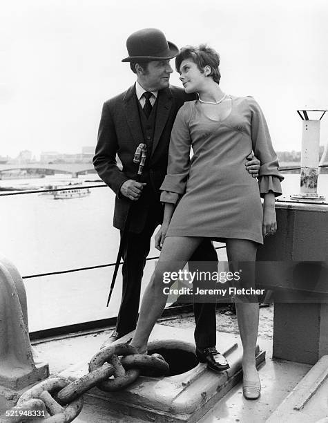 English actor Patrick Macnee and Canadian actress Linda Thorson on a boat moored on the River Thames in London, during a publicity photoshoot for the...