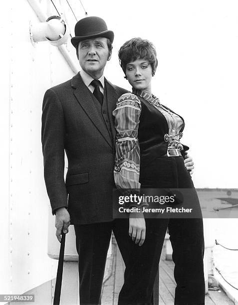 English actor Patrick Macnee and Canadian actress Linda Thorson on a boat moored on the River Thames in London, during a publicity photoshoot for the...