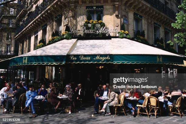 patrons sitting outside les deux magots cafe - les deux magots photos et images de collection