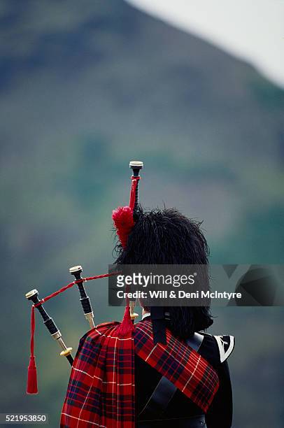 back view of bagpiper - bagpipes stock-fotos und bilder