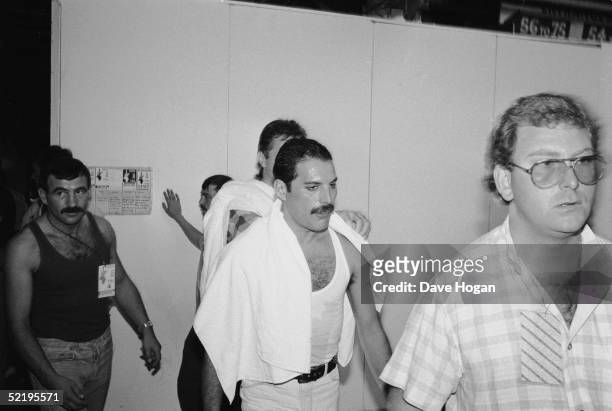 Rock star Freddie Mercury backstage at the Live Aid concert at Wembley, 13th July 1985. On the left is his boyfriend Jim Hutton.