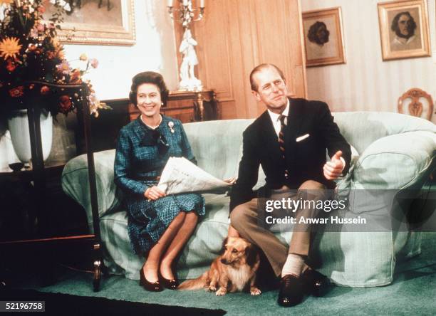 Queen Elizabeth II and Prince Philip, Duke of Edinburgh relax with their corgis and a newspaper at Balmoral Castle in 1974 in Balmoral, Scotland.